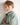 Young boy wearing a light green jumper with a logo on a white background