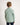 Young boy wearing a light green jumper with a logo on a white background