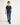 Young boy wearing a navy polo shirt and blue jeans on a white background