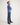 Young boy wearing a blue sweater and jeans standing against a white background