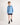 Boy wearing a light blue workshirt and dark shorts on a white background