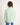Young girl wearing a light green jumper with a white background