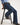 Person wearing blue jeans sitting on a black stool against a white background