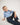 Young girl wearing a blue shirt and jeans sitting on the floor against a white background