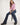 Person wearing a pink shirt and blue jeans sitting on a stool against a white background
