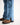 Close-up of blue jeans with brown boots on a white background