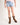 Girl wearing light blue denim shorts and brown cowboy boots on a white background