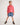 Young girl wearing a pink workshirt and denim shorts on a white background