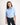 Young girl wearing a light blue workshirt and dark jeans on a white background