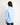 Young girl wearing a light blue workshirt and dark jeans on a white background