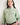 Girl wearing a green shirt with a pink collar against a white background