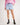 Girl wearing light blue rugger shorts, pink workshirt, and brown boots on a white background