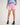 Girl wearing a light blue workshirt and pink shorts on a white background