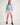 Girl wearing a light blue workshirt and pink shorts on a white background