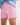 Girl wearing a light blue workshirt and pink shorts on a white background