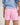 Girl wearing a light blue workshirt and pink shorts on a white background