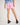 Girl wearing a light blue workshirt and pink shorts on a white background