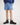 Boy wearing a blue workshirt and shorts with brown boots on a white background