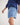 Boy wearing a blue workshirt and shorts with brown boots on a white background