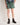 Boy wearing green shorts and brown boots on a plain background