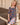 Young girl in a floral dress standing on a wooden deck.