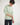Person wearing a light green hoodie and dark pants on a white background