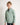 Young boy wearing a light green jumper with a logo on a white background