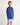 Young boy wearing a dark blue workshirt and light blue shorts on a white background