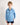 Young boy wearing a light blue workshirt with a collar on a plain background