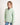 Young girl wearing a light green jumper with a white background