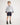 Boy wearing a striped shirt and navy rugger shorts on a white background