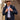 Man wearing a navy jacket, light blue shirt, and beige cowboy hat standing next to a tree.